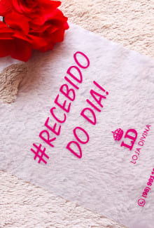 Sacola plástica alça vazada na cor branca, com material transparente. Tem uma frase escrita "#Recebido do dia!" na cor rosa.