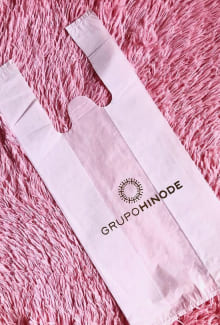 Sacola plástica camiseta na cor branca, com a logomarca Grupo Hinode.